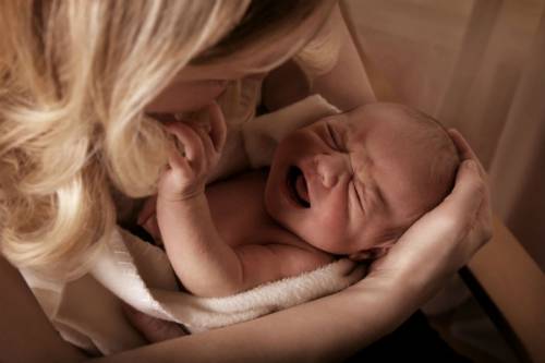 Новорожденный ребенок плачет у мамы на руках