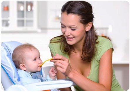 Мама кормит ребенка с ложечки