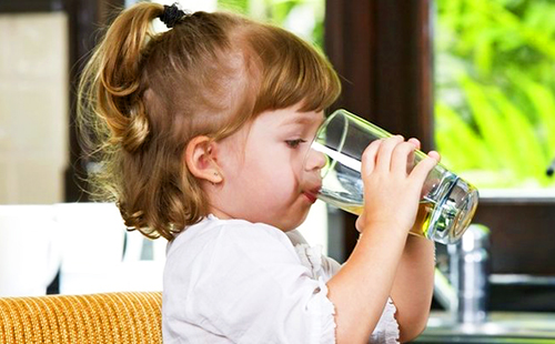 Девчушка пьёт воду из стеклянного стакана