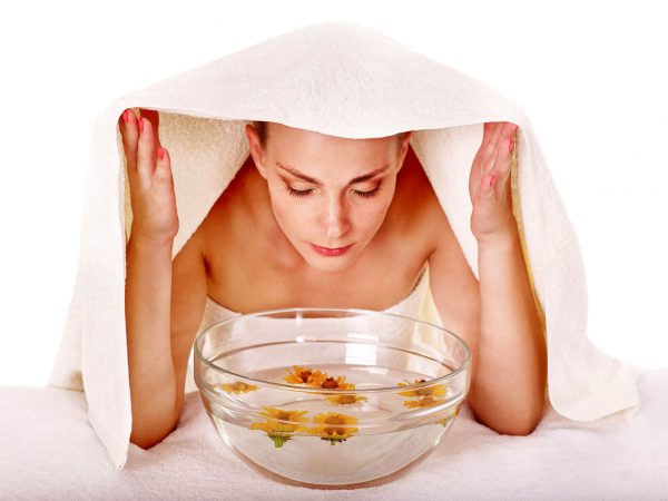 Девушка распаривает кожу лица над ванночкой